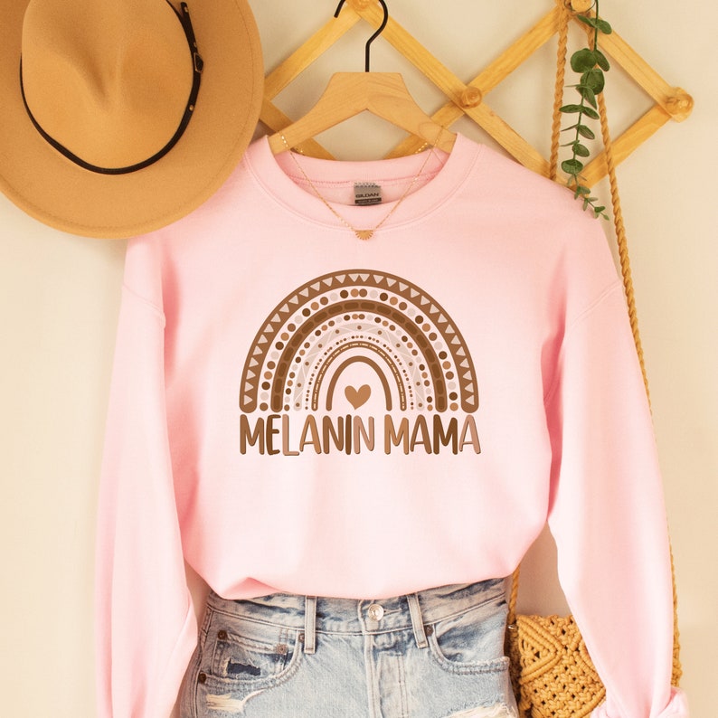 pink  unisex melanin mom sweatshirt with a graphic of a rainbow in shades of brown with the words melanin mama underneath the rainbow