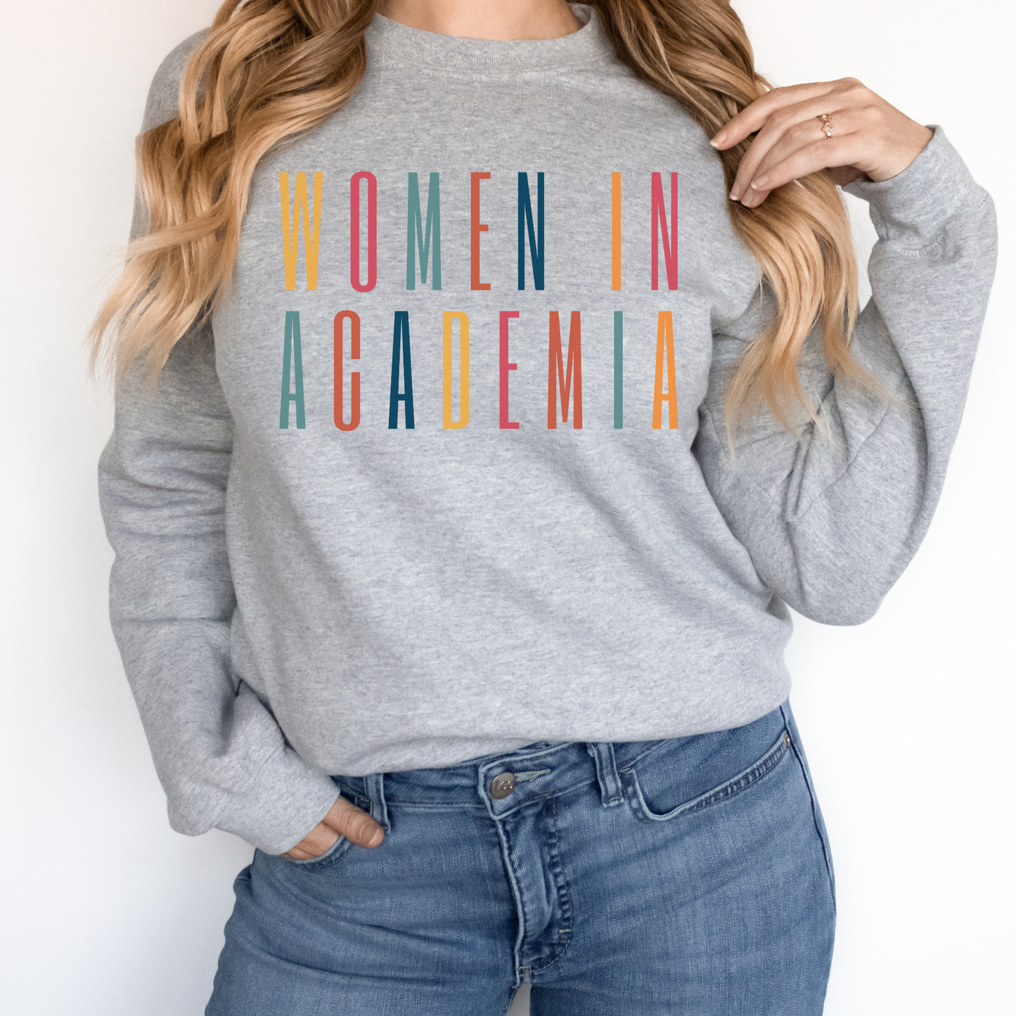 Professor gifts, Unisex sweatshirt on model with multicolor letters that say Women in Academia. 