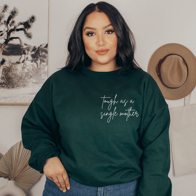 forest green sweatshirt that says "tough as a single mother" on the pocket area (no pocket) in cursive font. Our sweatshirts are the best gifts for single moms