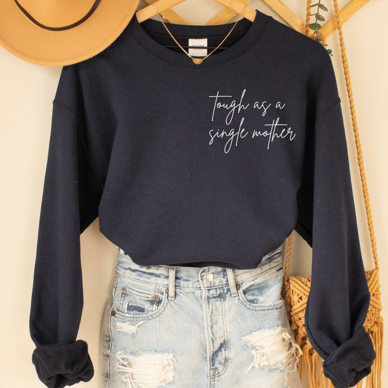 navy blue sweatshirt that says "tough as a single mother" on the pocket area (no pocket) in cursive font. Our sweatshirts are the best gifts for single moms