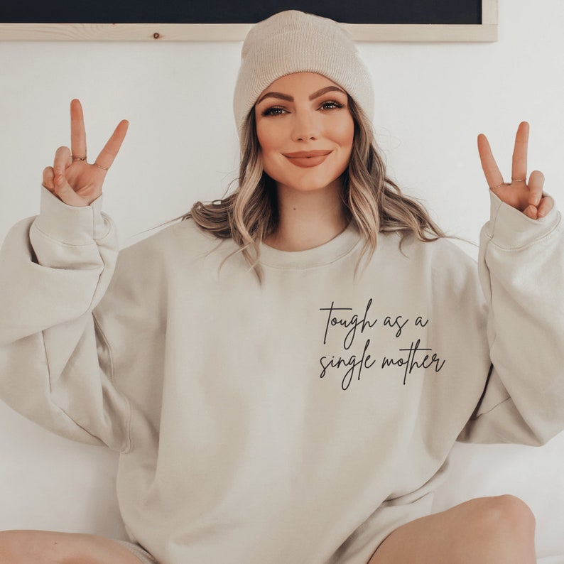 beige sweatshirt that says "tough as a single mother" on the pocket area (no pocket) in cursive font. Our sweatshirts are the best gifts for single moms