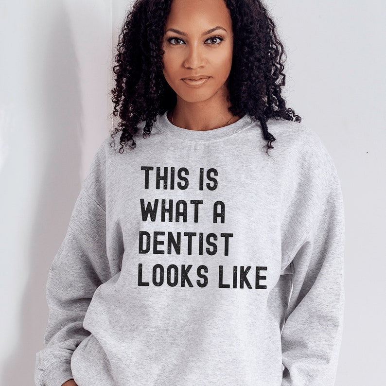 light gray unisex dentist sweatshirt that says this is what a dentist looks like in all black, capital letters