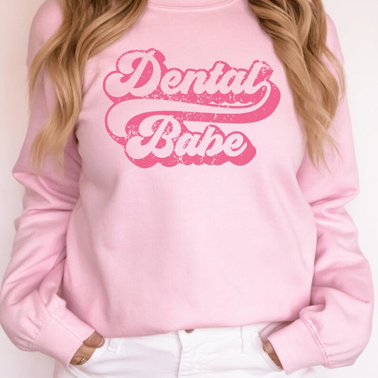pink unisex dental hygienist sweatshirt that says "dental babe" in retro styled pink lettering with an antique and vintage style
