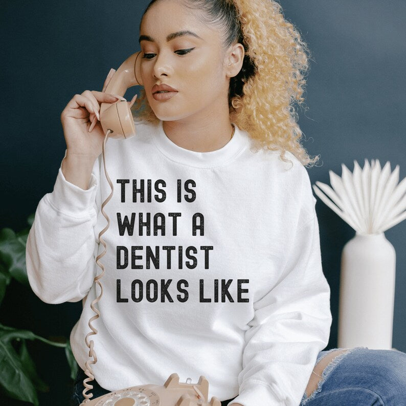 white unisex dentist sweatshirt that says this is what a dentist looks like in all black, capital letters