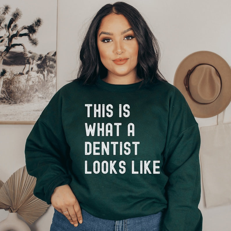 forest green unisex dentist sweatshirt that says this is what a dentist looks like in all white, capital letters