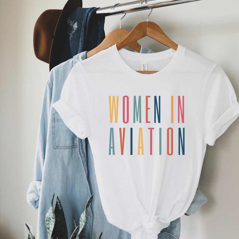 white unisex t-shirt with multicolored letters that say women in aviation