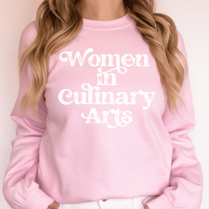 pink unisex sweatshirt that says women in culinary arts in white letters with a whimsical font; perfect gift for culinary students