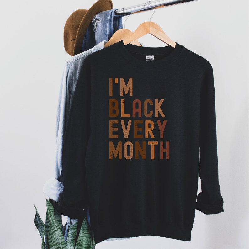 black Beige unisex I am black every month shirt, with the words written in all capital, multicolored shades of brown 