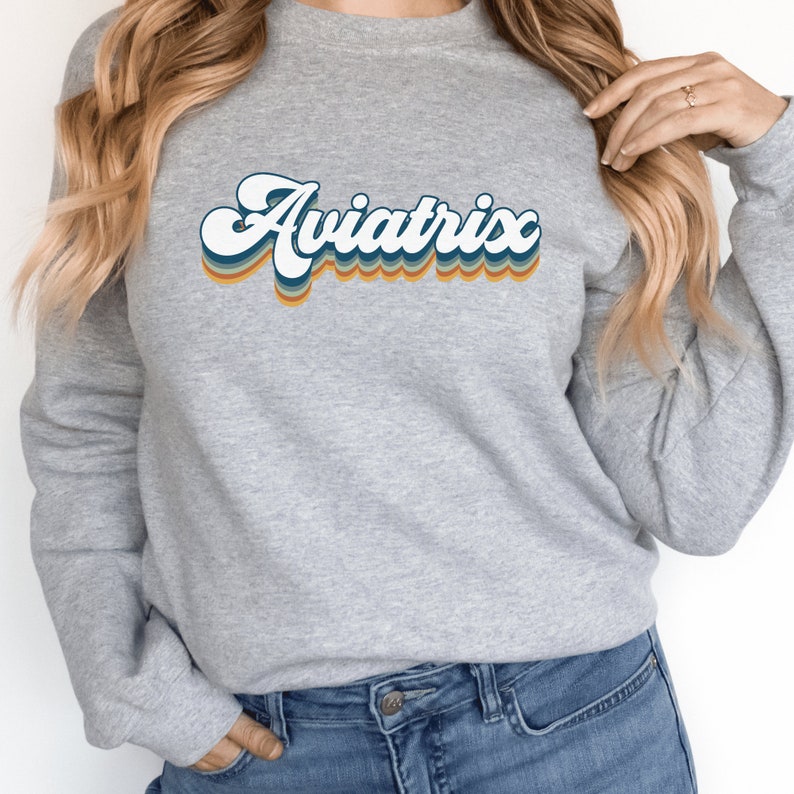 gray unisex sweatshirt with retro styled lettering with shadowing that says Aviatrix, female pilot shirts