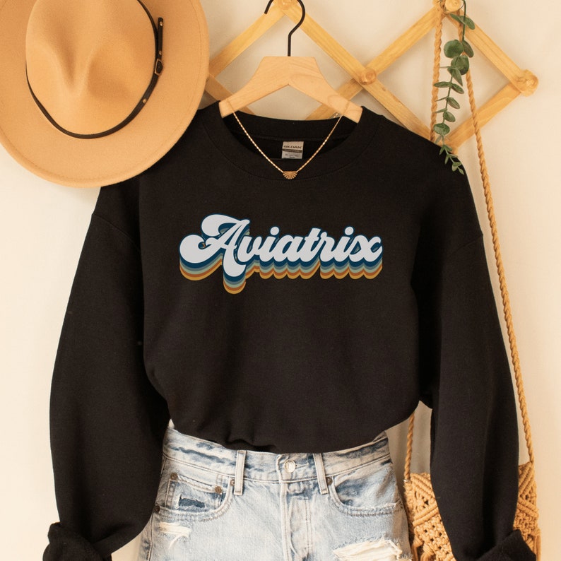 black unisex sweatshirt with retro styled lettering with shadowing that says Aviatrix, female pilot shirts