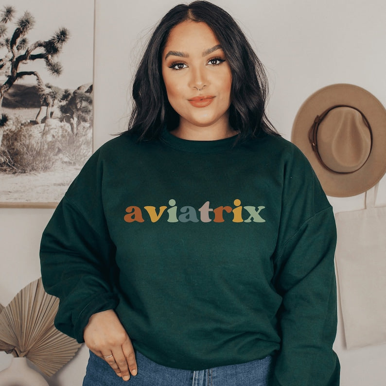 forest green unisex sweatshirt with multicolored lettering with shadowing that says Aviatrix