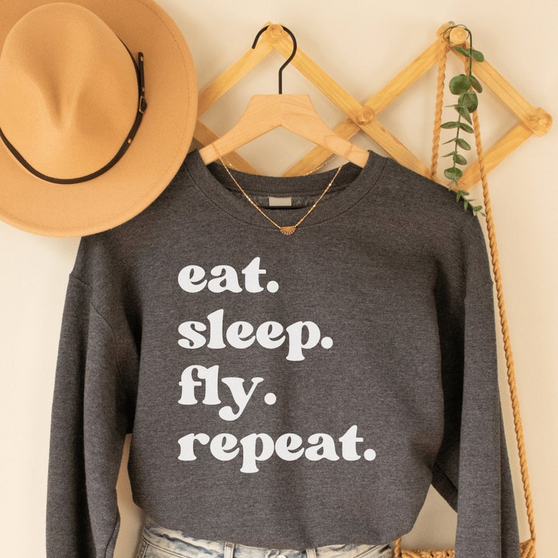 dark gray heather unisex wanderlust sweatshirt that says eat sleep fly repeat