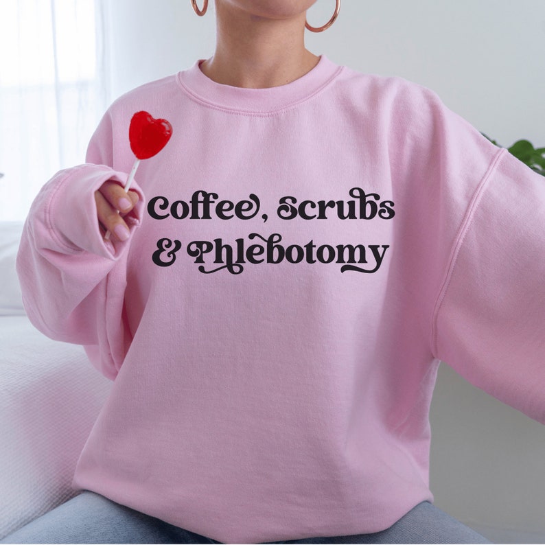 our gifts for a phlebotomist include this pink unisex sweatshirt that says coffee, scrubs, & phlebotomy