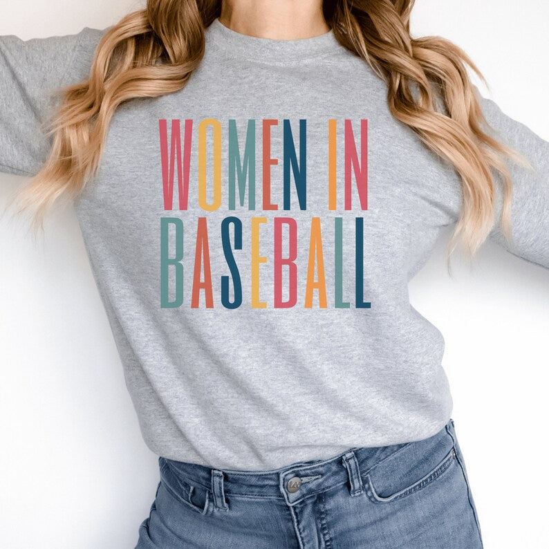 Gray unisex sweatshirt with multicolored letters that say women in baseball in all caps