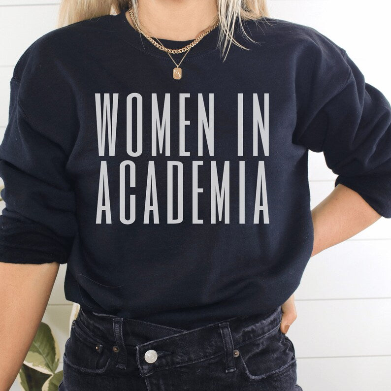 professor gifts, black unisex sweatshirt on female model with "Women in Academia" in white lettering across the front