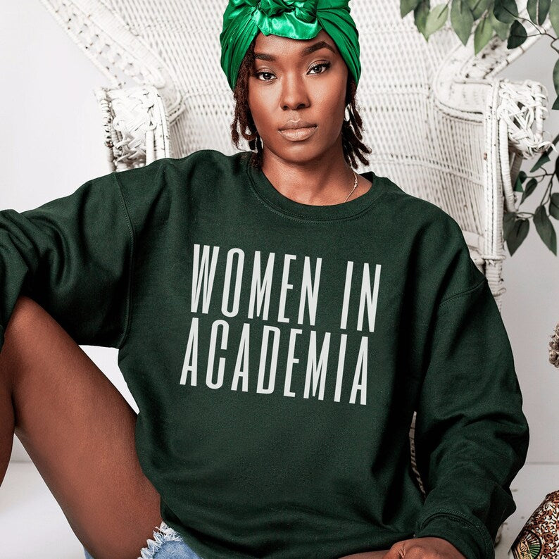 professor gifts, forest green unisex sweatshirt on female model with "Women in Academia" in white lettering across the front