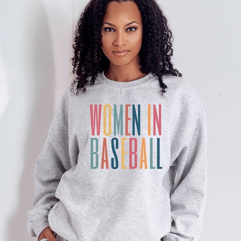 Light Gray unisex sweatshirt with multicolored letters that say women in baseball in all caps