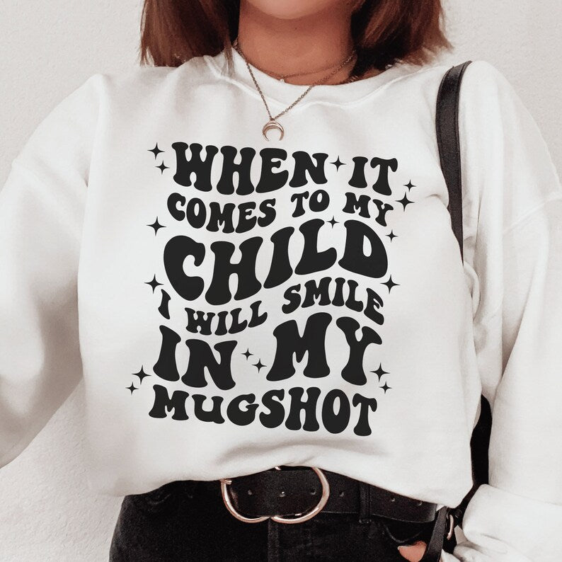 white unisex "mama sweatshirt" that says when it comes to my child i will smile in my mugshot in all capital retro styled black letters