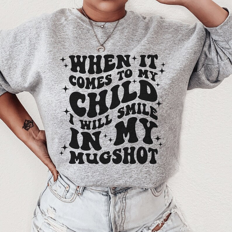 gray unisex "mama sweatshirt" that says when it comes to my child i will smile in my mugshot in all capital retro styled black letters