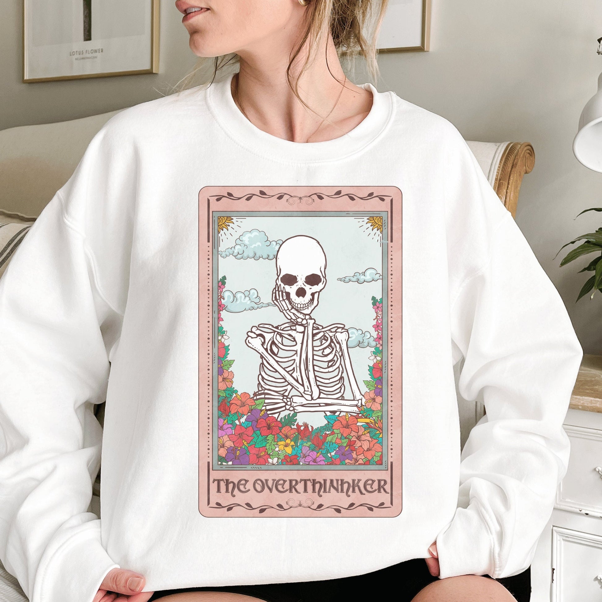 white unisex overthinker sweatshirt with a graphic of a tarot card with skeleton graphic that says the overthinker