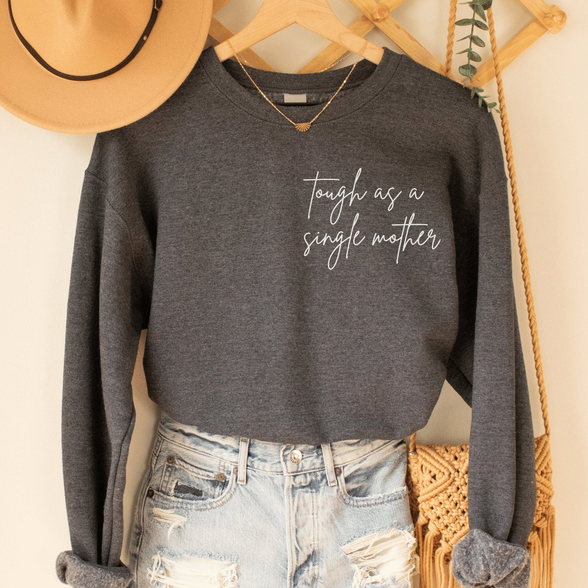 dark  gray heather sweatshirt that says "tough as a single mother" on the pocket area (no pocket) in cursive font. Our sweatshirts are the best gifts for single moms