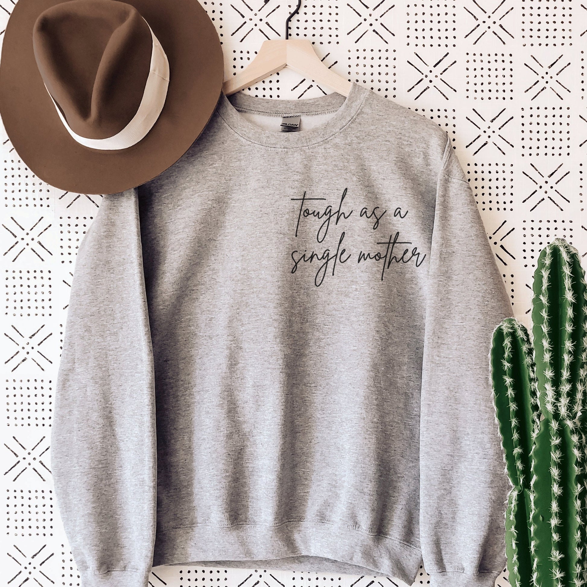 gray sweatshirt that says "tough as a single mother" on the pocket area (no pocket) in cursive font. Our sweatshirts are the best gifts for single moms