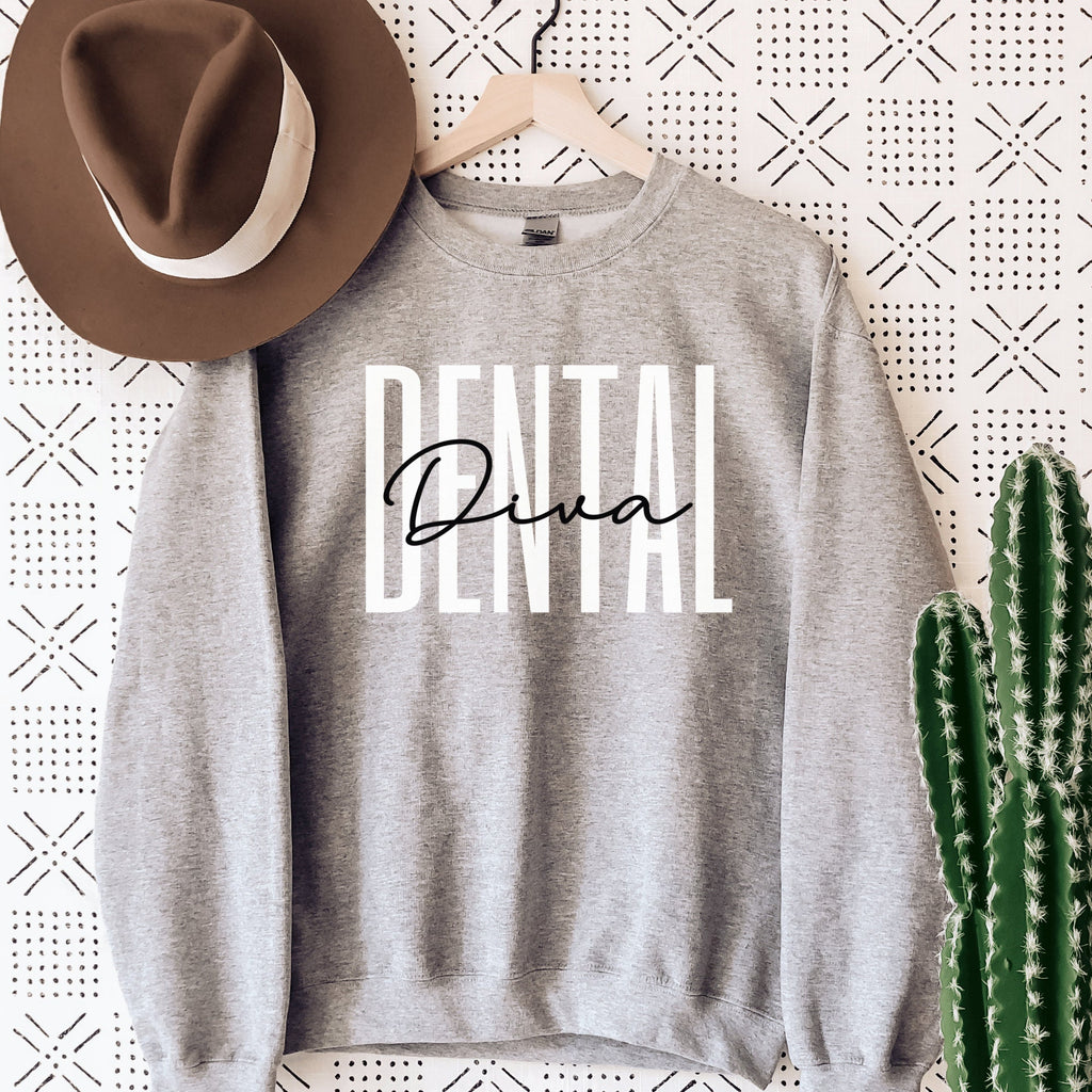 gray unisex dental hygienist sweatshirt that says dental in all white capital letters with the word diva in black script overlaying the word dental