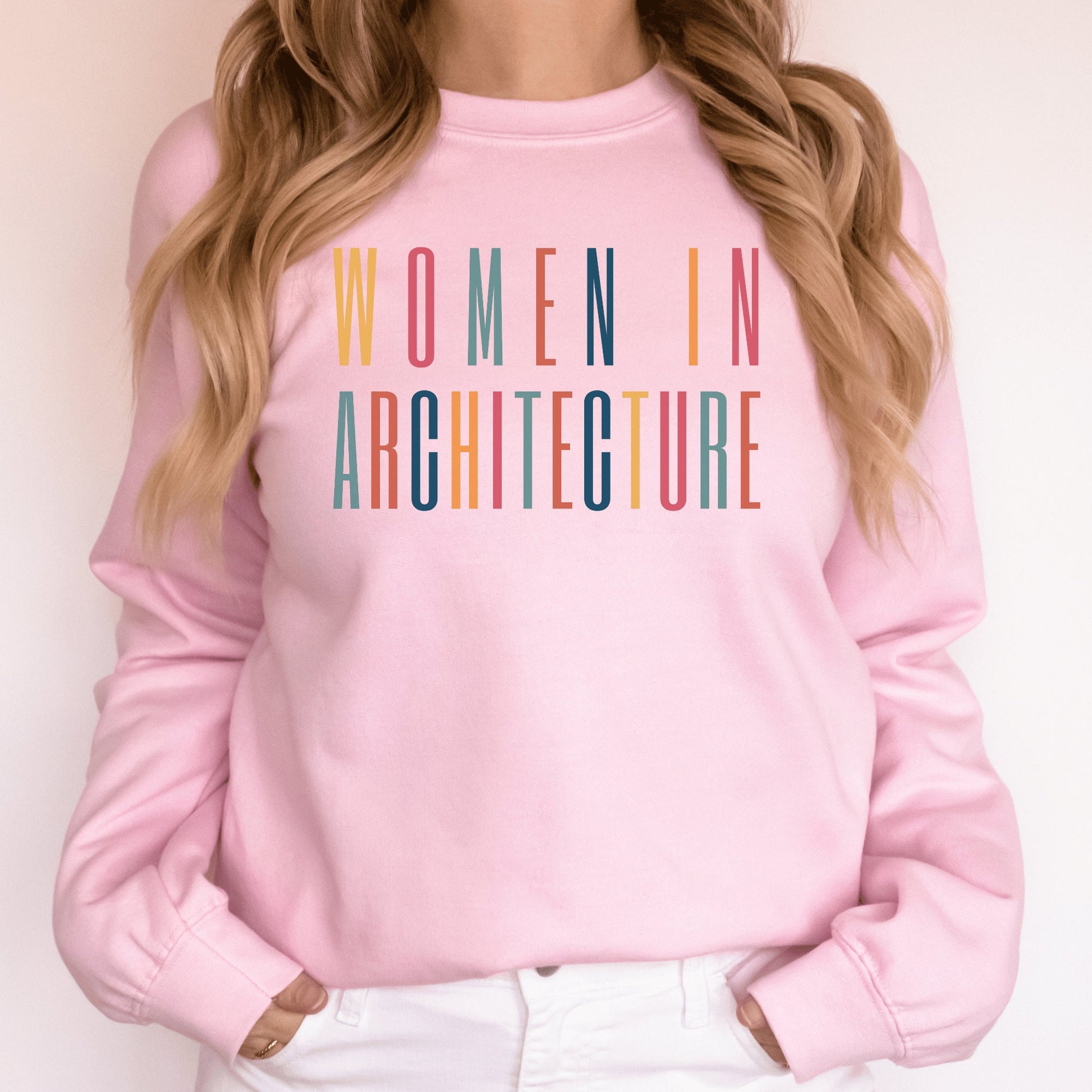 pink  unisex sweatshirt with women in architecture written in capital, multicolored letters. Our apparel makes great architecture student gifts