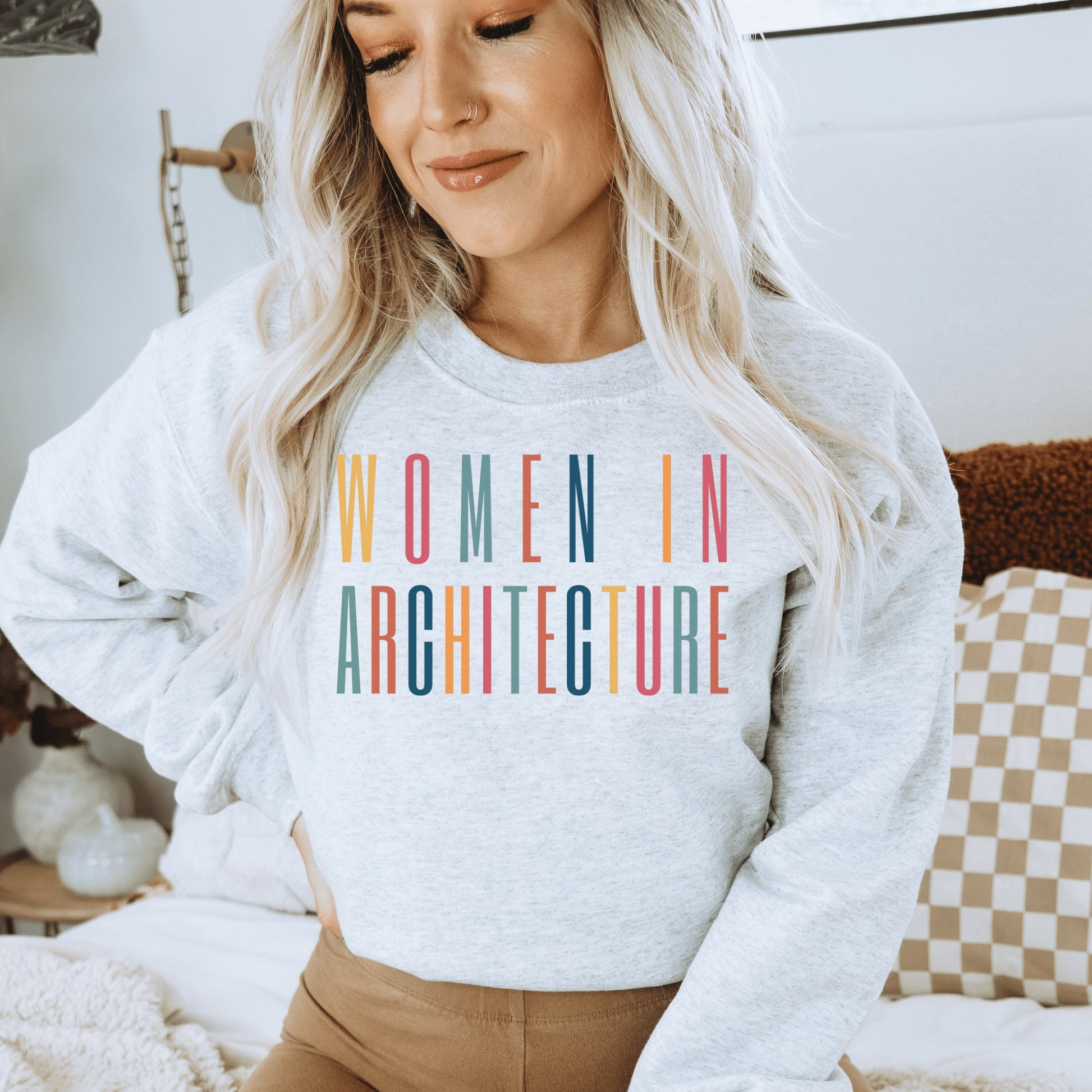 light gray  unisex sweatshirt with women in architecture written in capital, multicolored letters. Our apparel makes great architecture student gifts