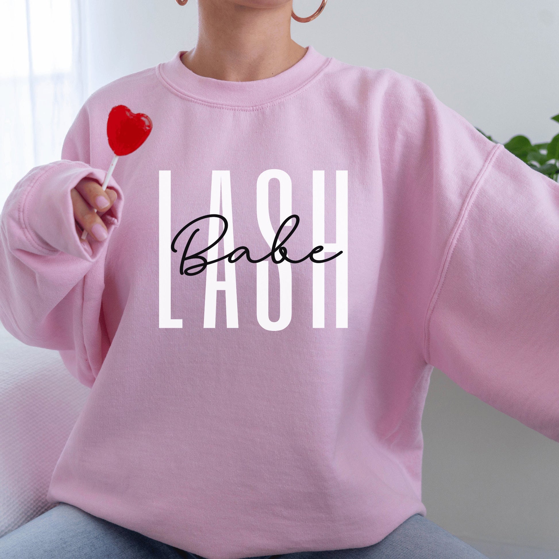 pink unisex sweatshirt lash tech gift that says lash in white capital letters and the word babe across in black cursive font