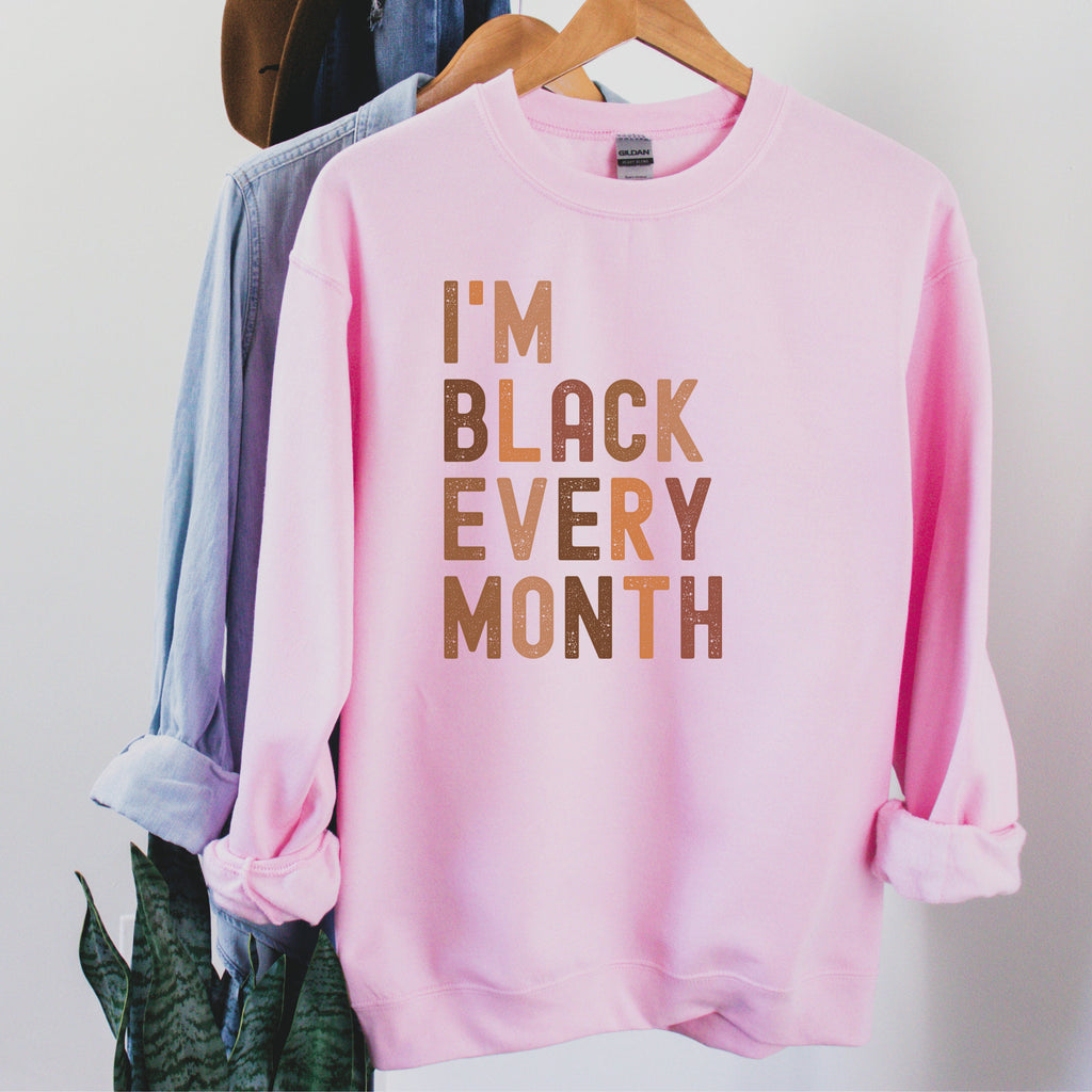 pink Beige unisex I am black every month shirt, with the words written in all capital, multicolored shades of brown 