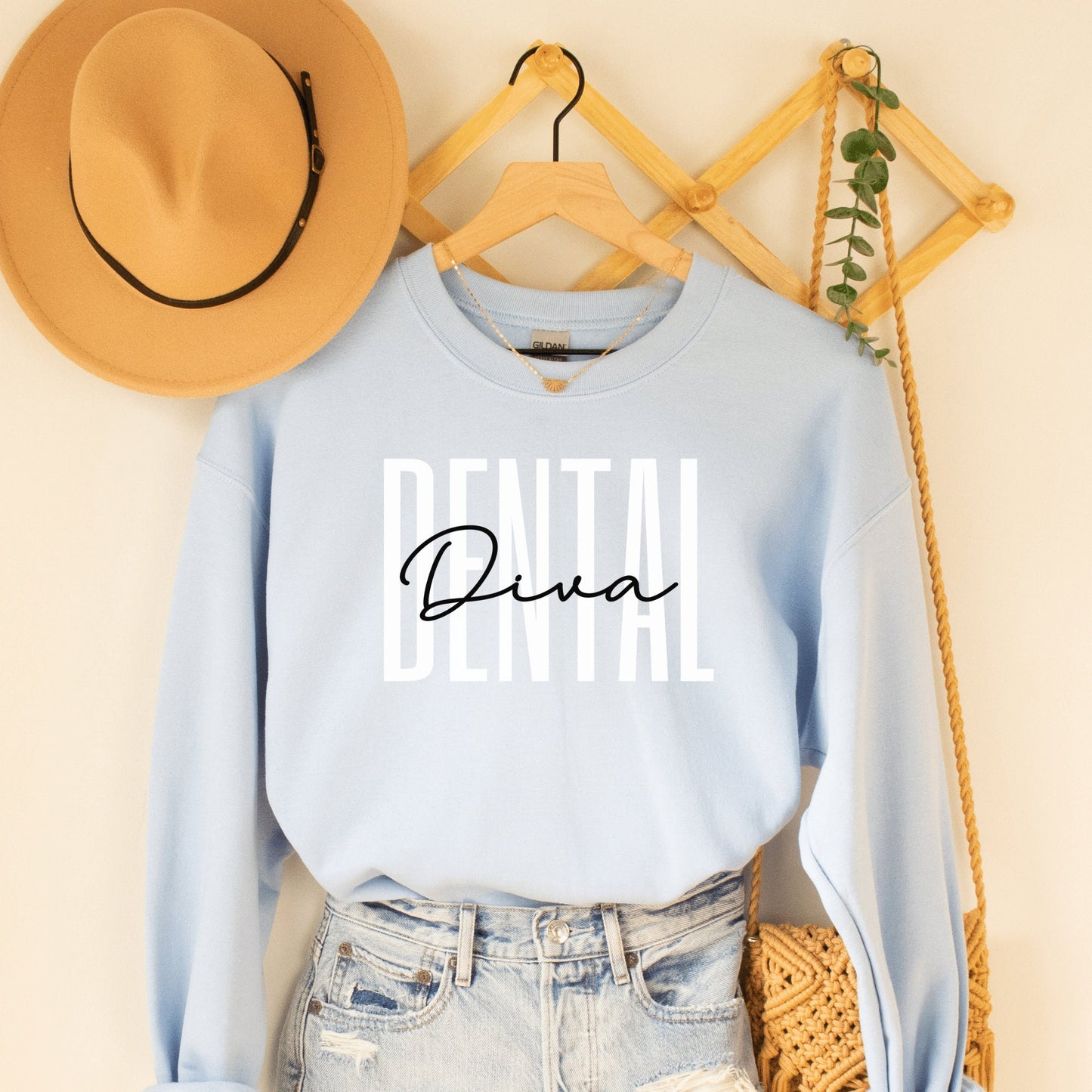 light blue unisex dental hygienist sweatshirt that says dental in all white capital letters with the word diva in black script overlaying the word dental