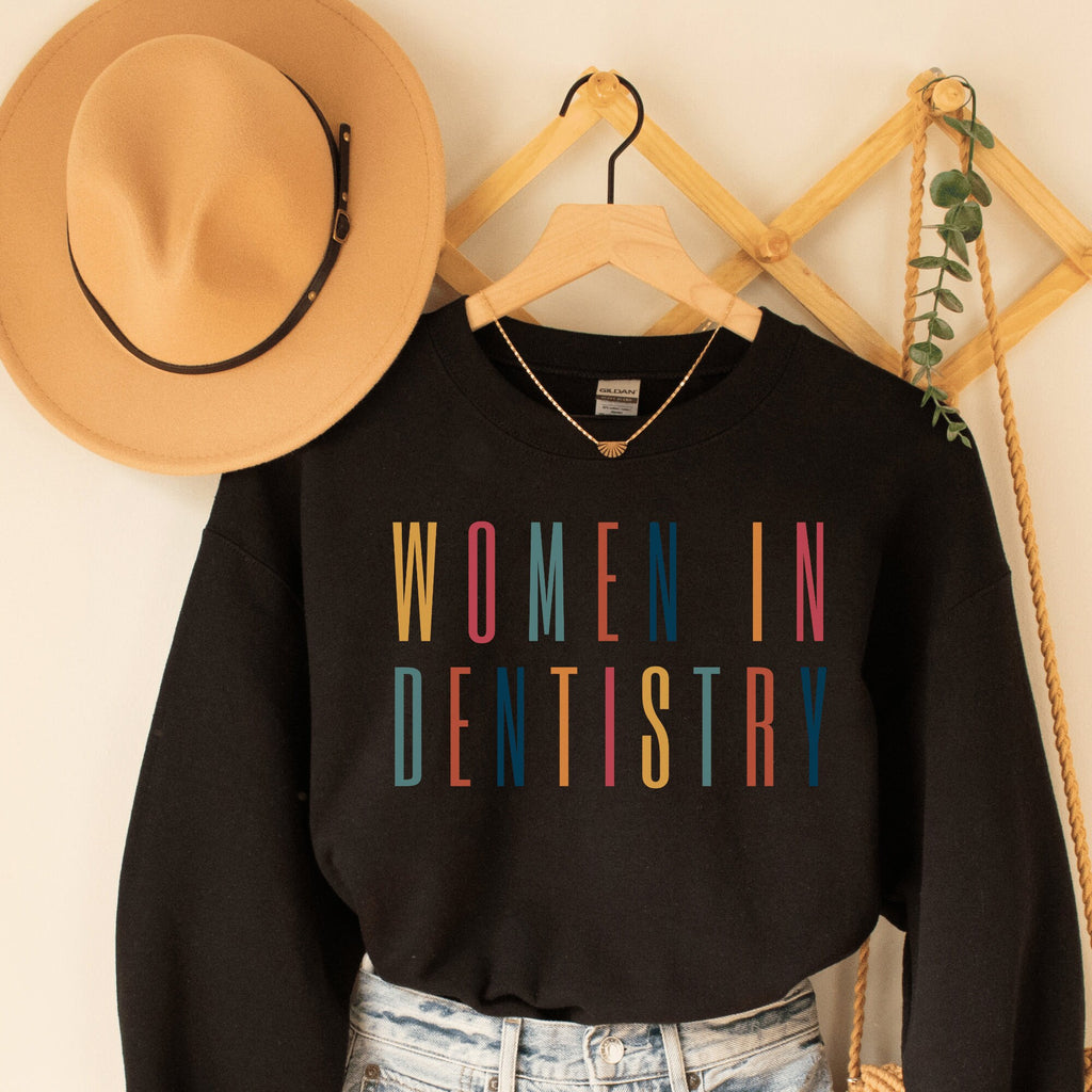 black unisex sweatshirt that says "women in dentistry" in all capital multicolored letters, perfect graduation gifts for dentists
