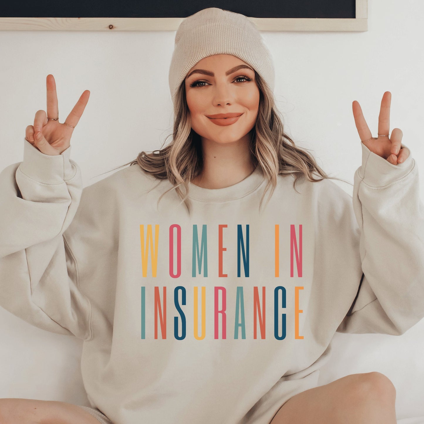 beige unisex sweatshirt that says "women in insurance" in all capital, multicolored letters and makes the perfect gift for an insurance agent