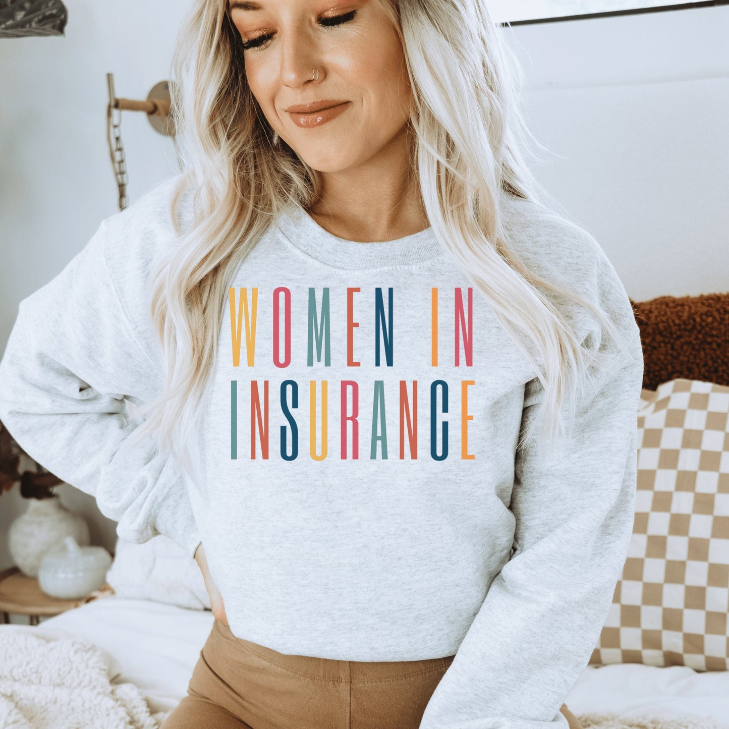 light gray unisex sweatshirt that says "women in insurance" in all capital, multicolored letters and makes the perfect gift for an insurance agent