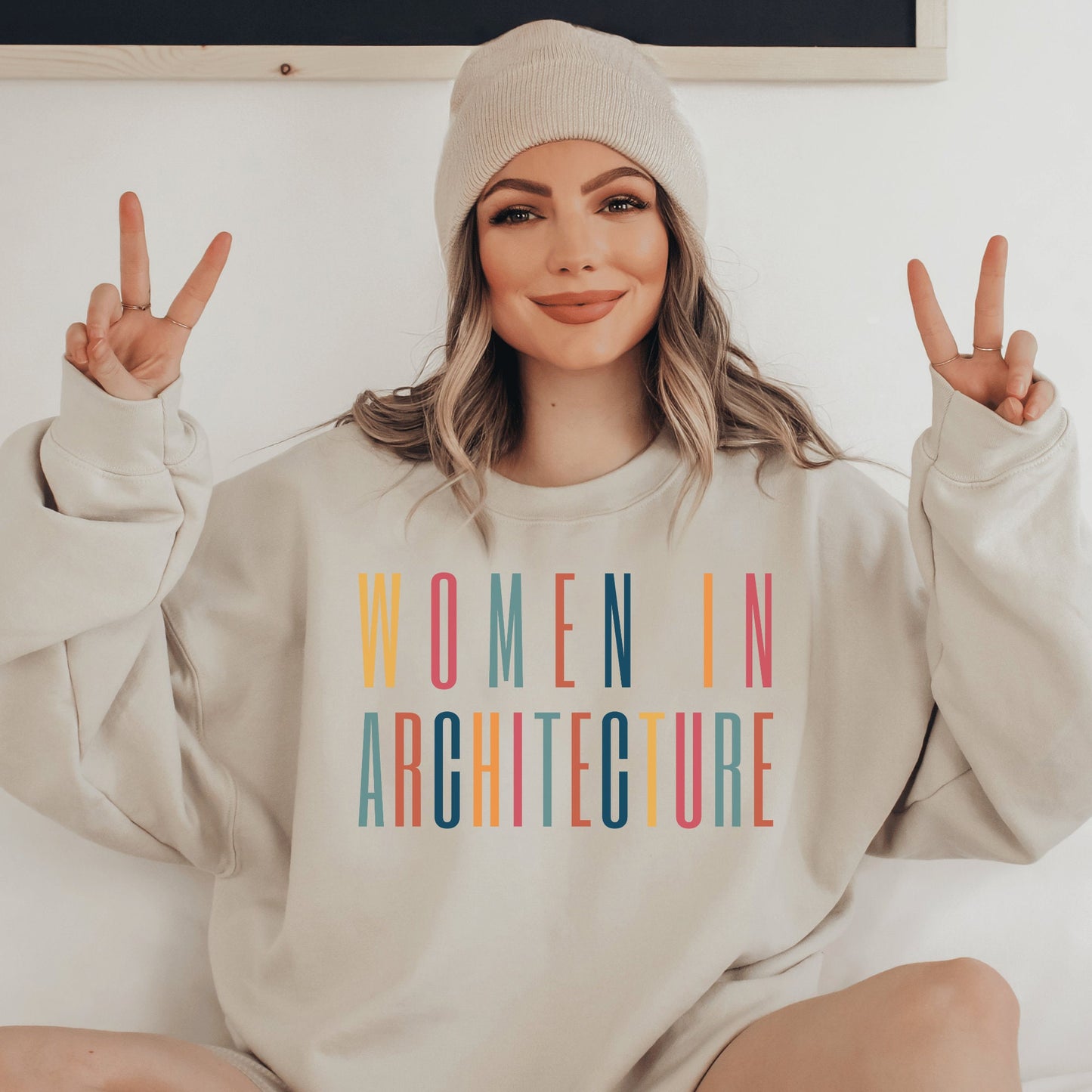 beige unisex sweatshirt with women in architecture written in capital, multicolored letters. Our apparel makes great architecture student gifts