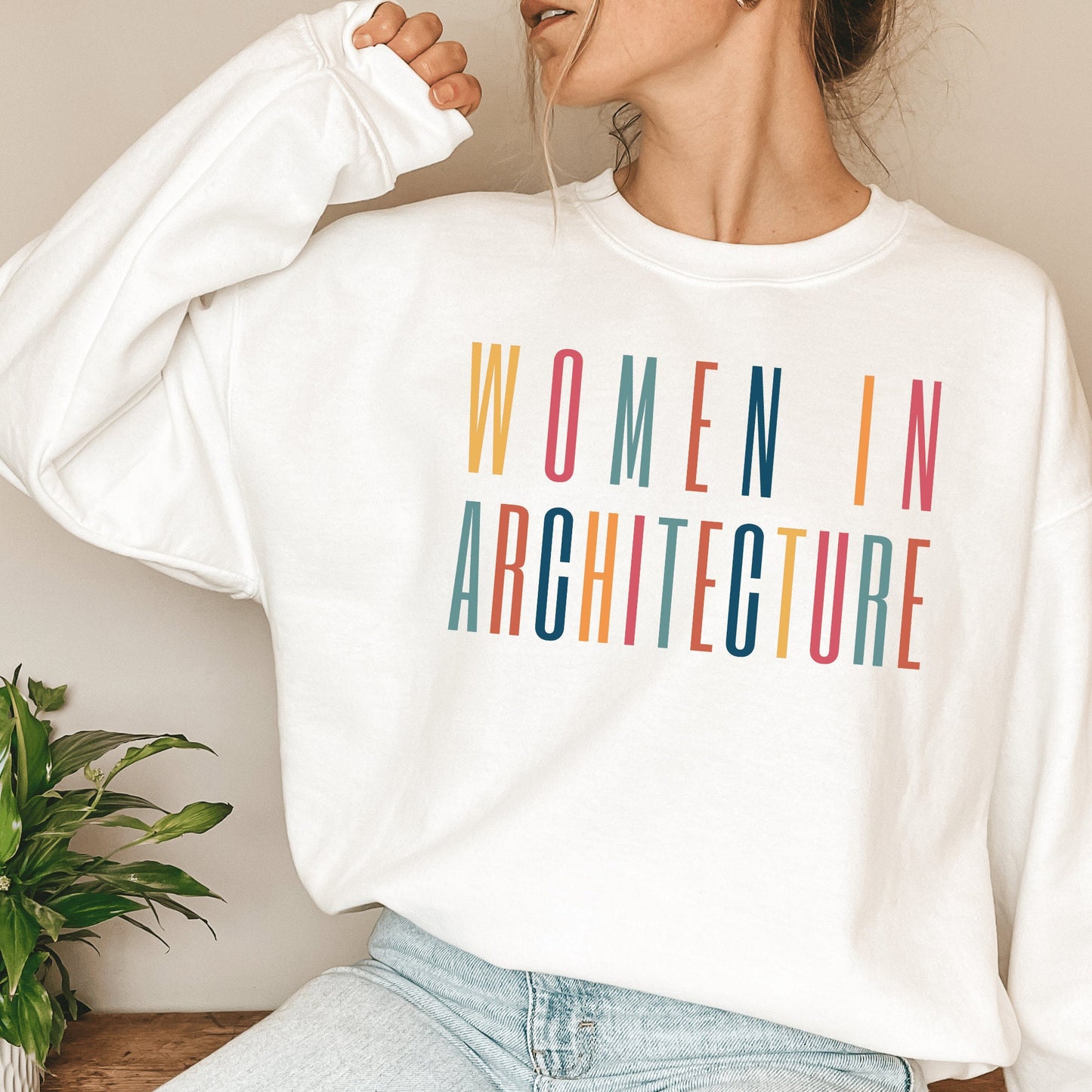 white unisex sweatshirt with women in architecture written in capital, multicolored letters. Our apparel makes great architecture student gifts