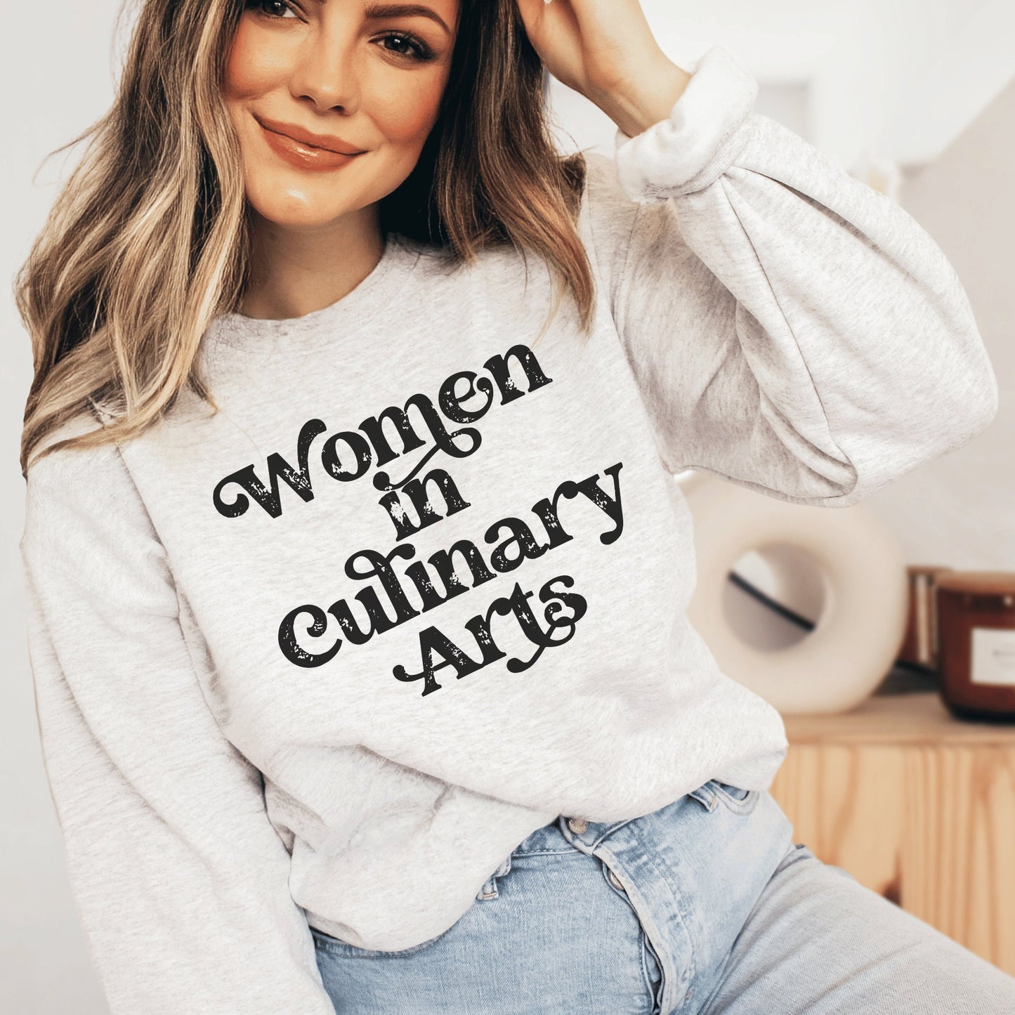 light gray unisex sweatshirt that says women in culinary arts in black letters with a whimsical font; perfect gift for culinary students