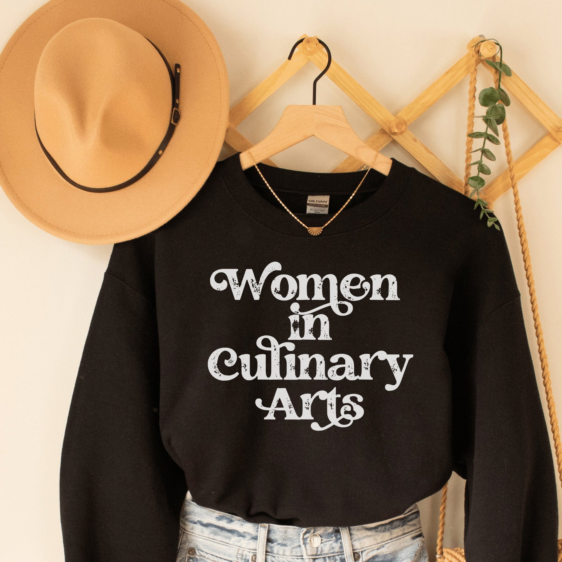 black unisex sweatshirt that says women in culinary arts in white letters with a whimsical font; perfect gift for culinary students