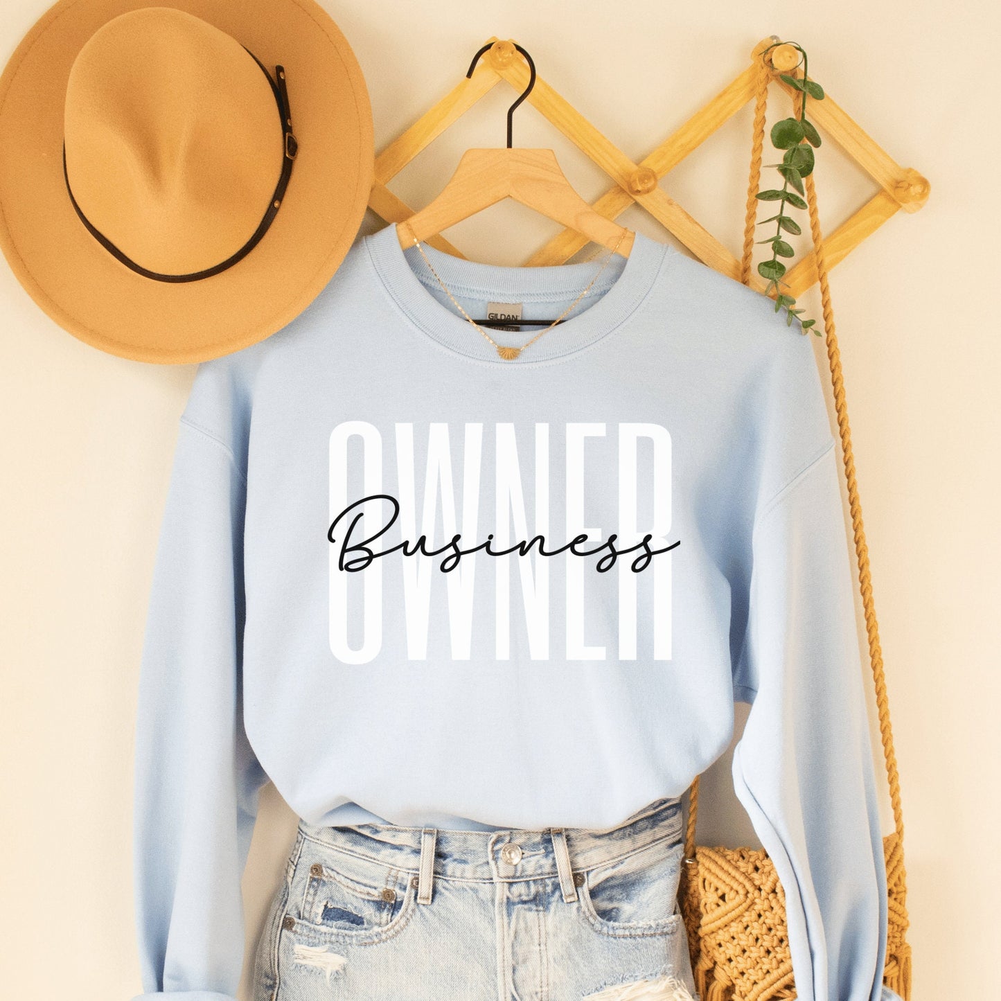 light blue unisex small business sweatshirt that says owner in all capital white letters and the word business across it in black script lettering