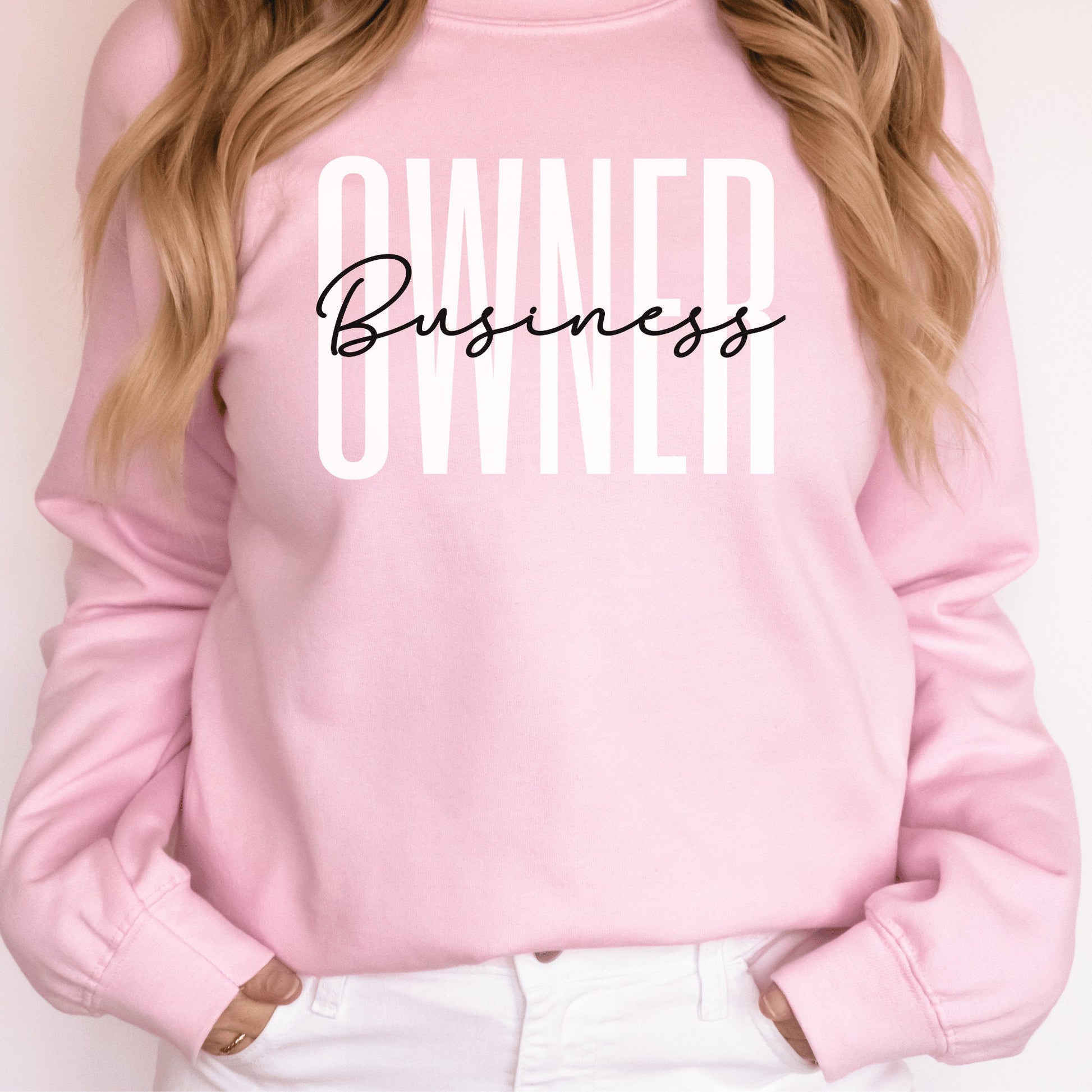 pink unisex small business sweatshirt that says owner in all capital white letters and the word business across it in black script lettering