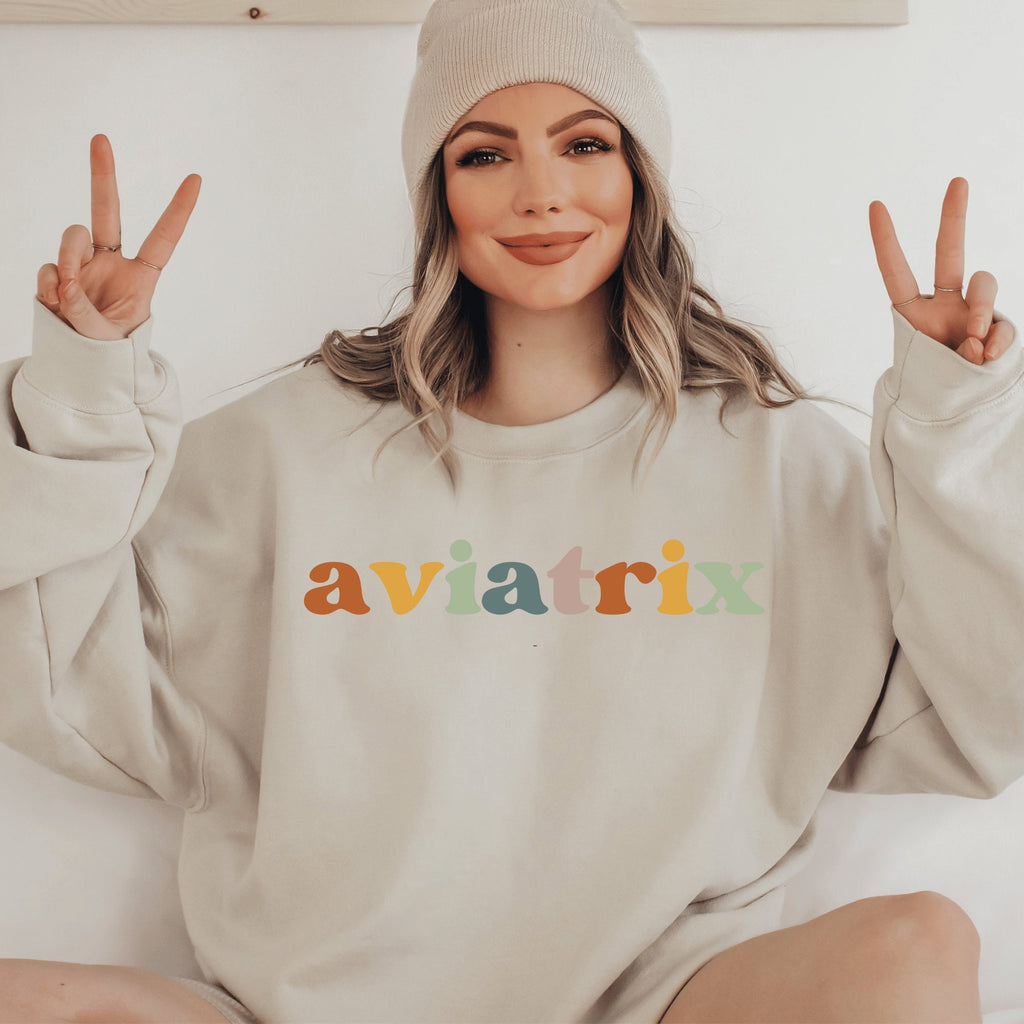 beige unisex sweatshirt with multicolored lettering with shadowing that says Aviatrix