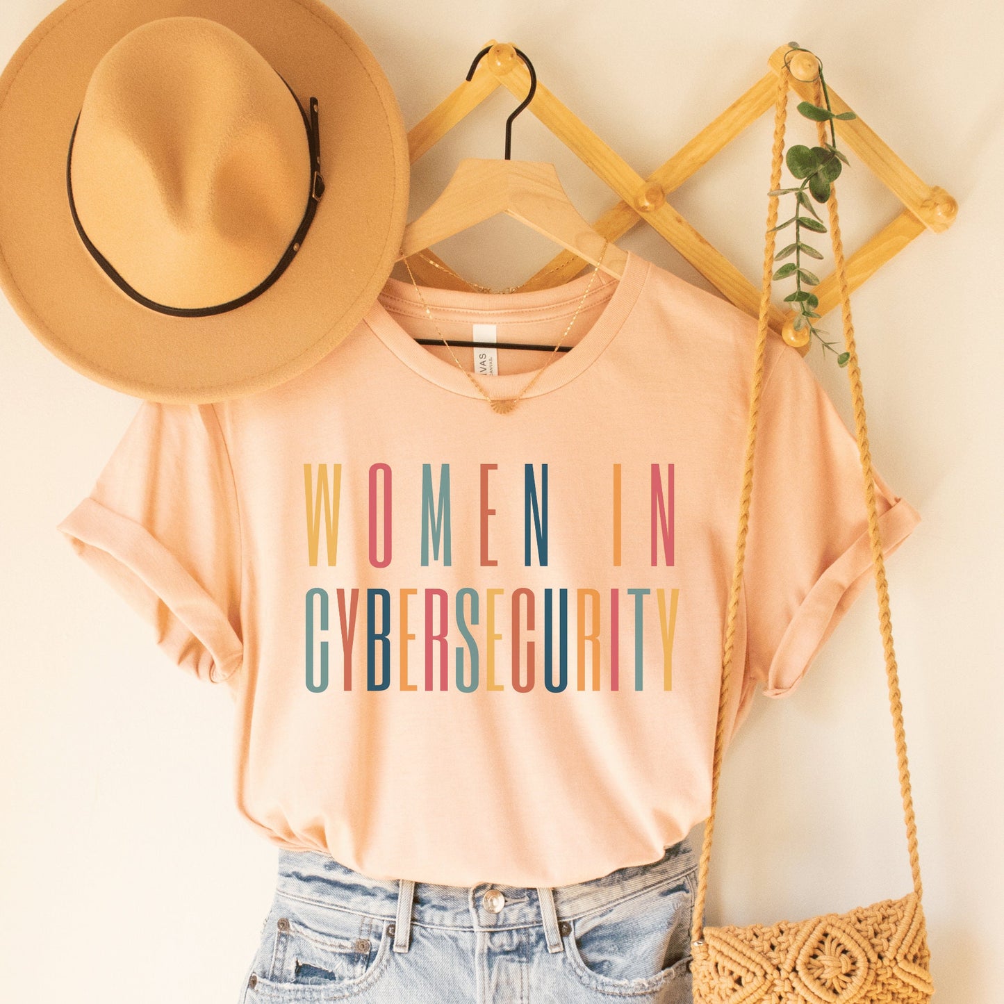 heather peach unisex t-shirt that says women in cybersecurity in all capital, multicolored letters, this is a cyber security gift idea