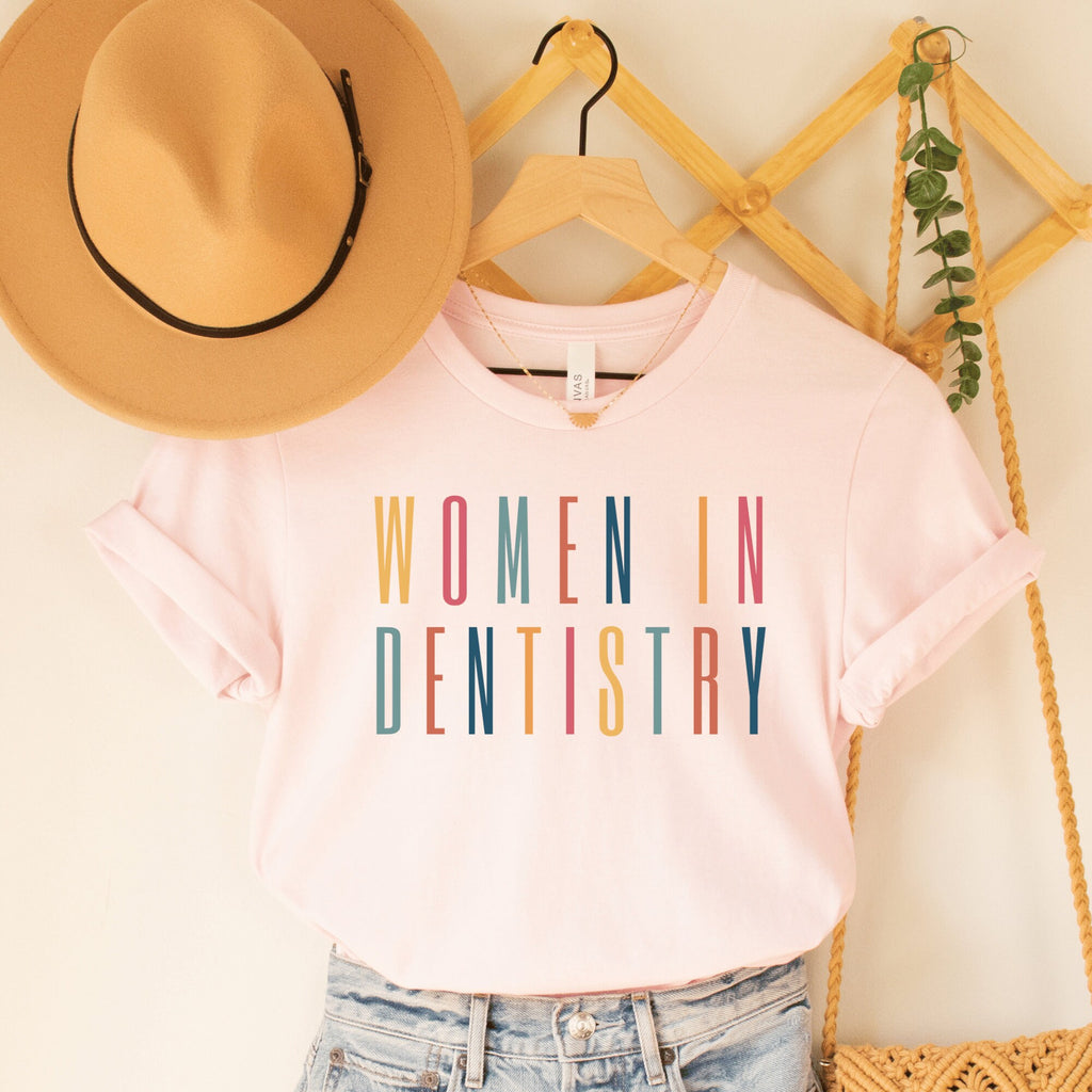 pink unisex dental shirt that says women in dentistry in all capital multicolored letters, perfect graduation gift for dentists
