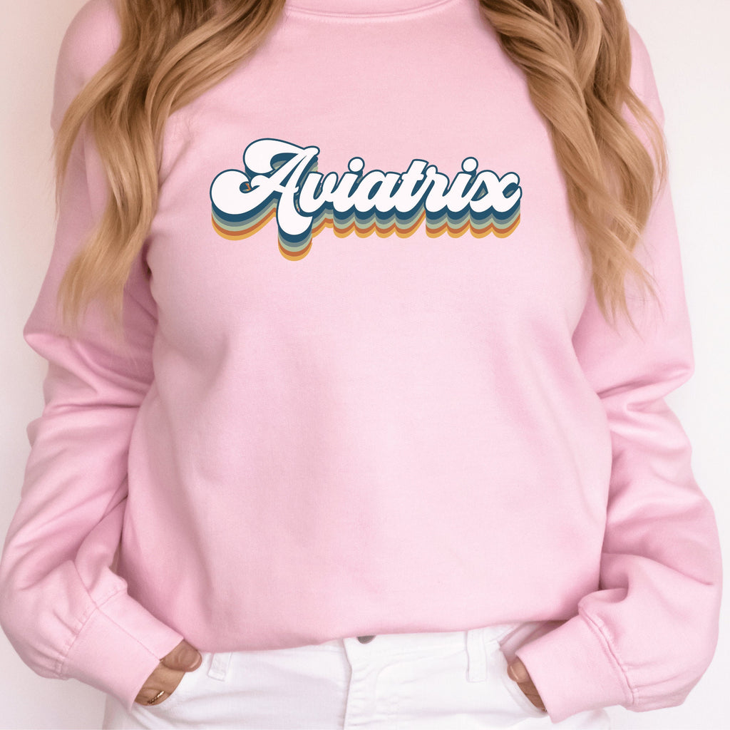 light pink unisex sweatshirt with retro styled lettering with shadowing that says Aviatrix, female pilot shirts
