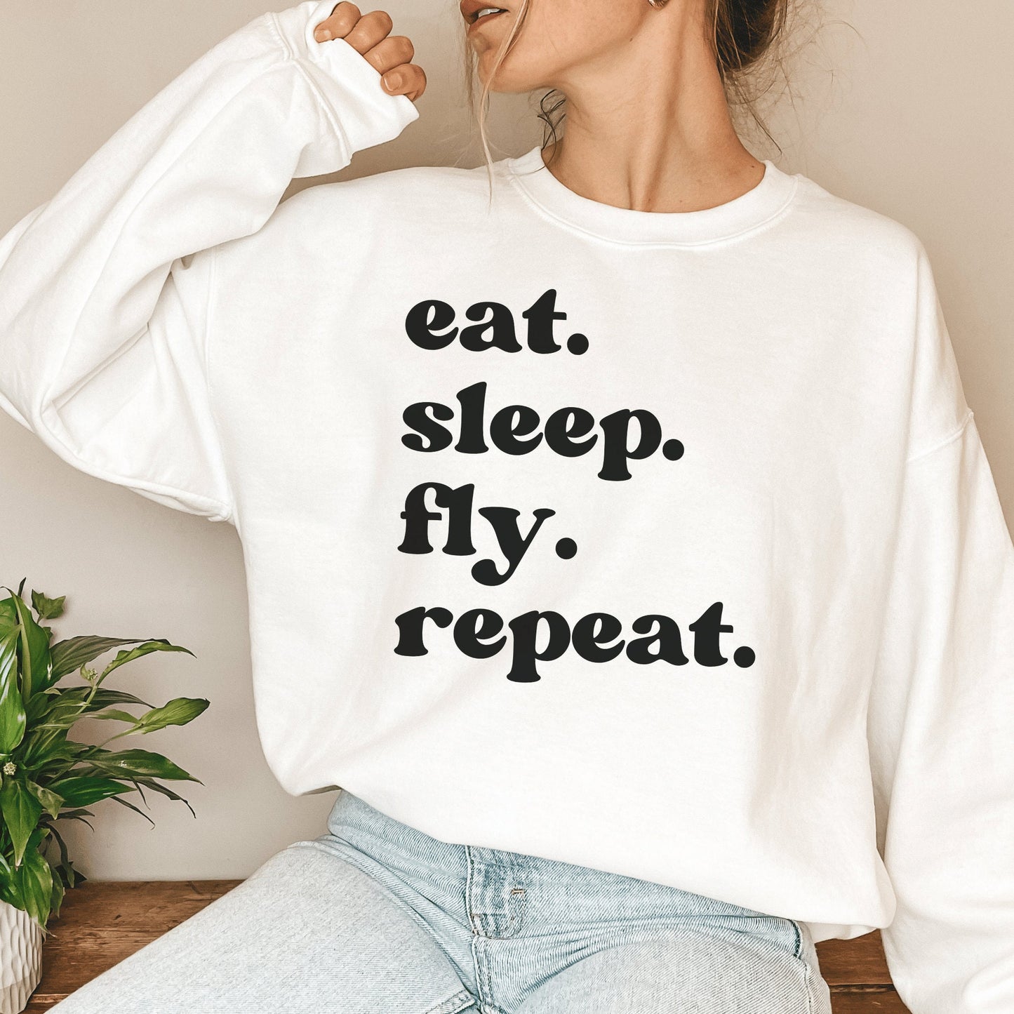 white unisex wanderlust sweatshirt that says eat sleep fly repeat