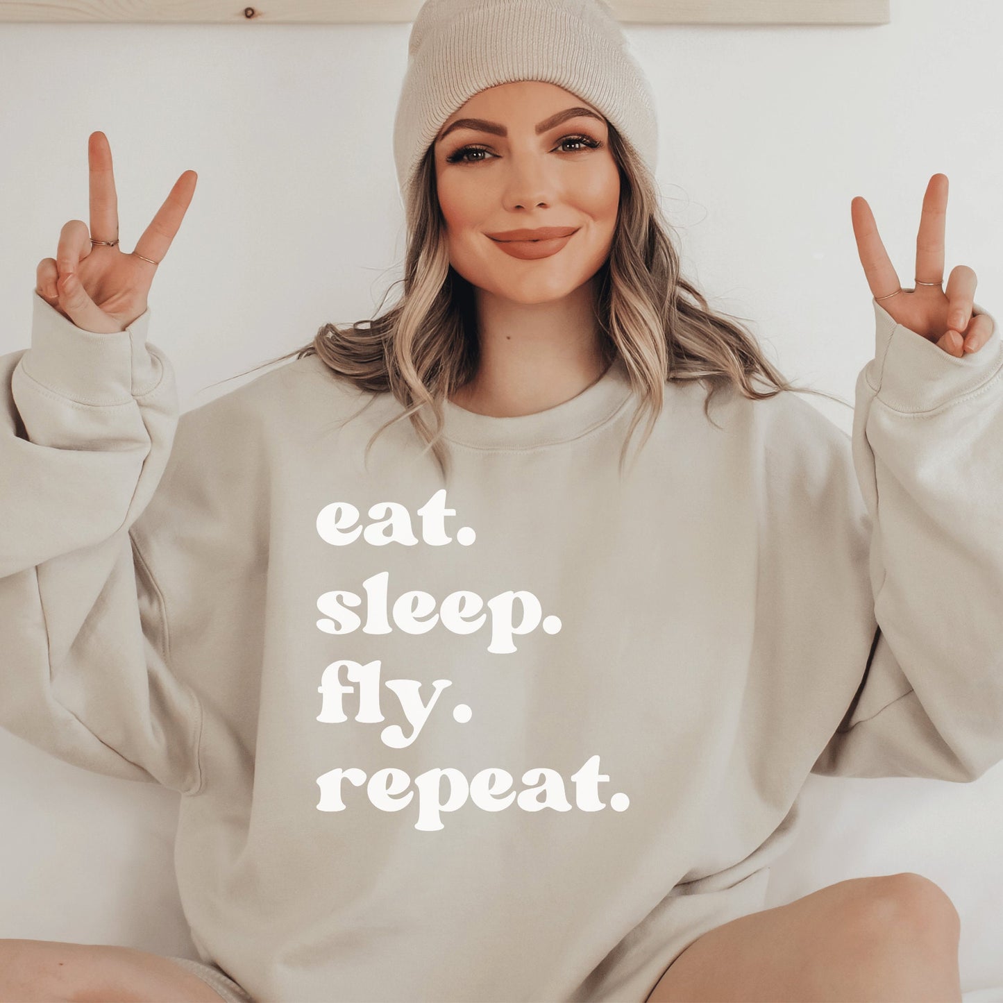 beige unisex wanderlust sweatshirt that says eat sleep fly repeat