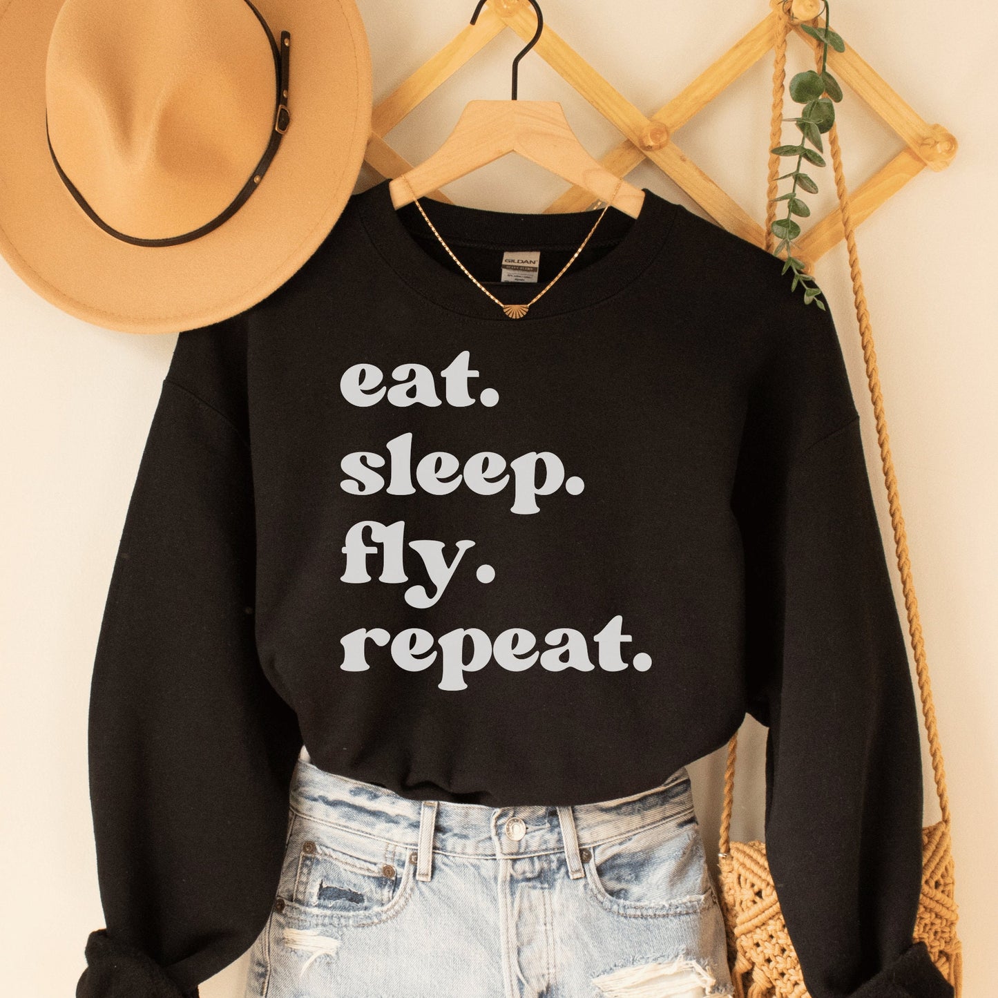 black unisex wanderlust sweatshirt that says eat sleep fly repeat