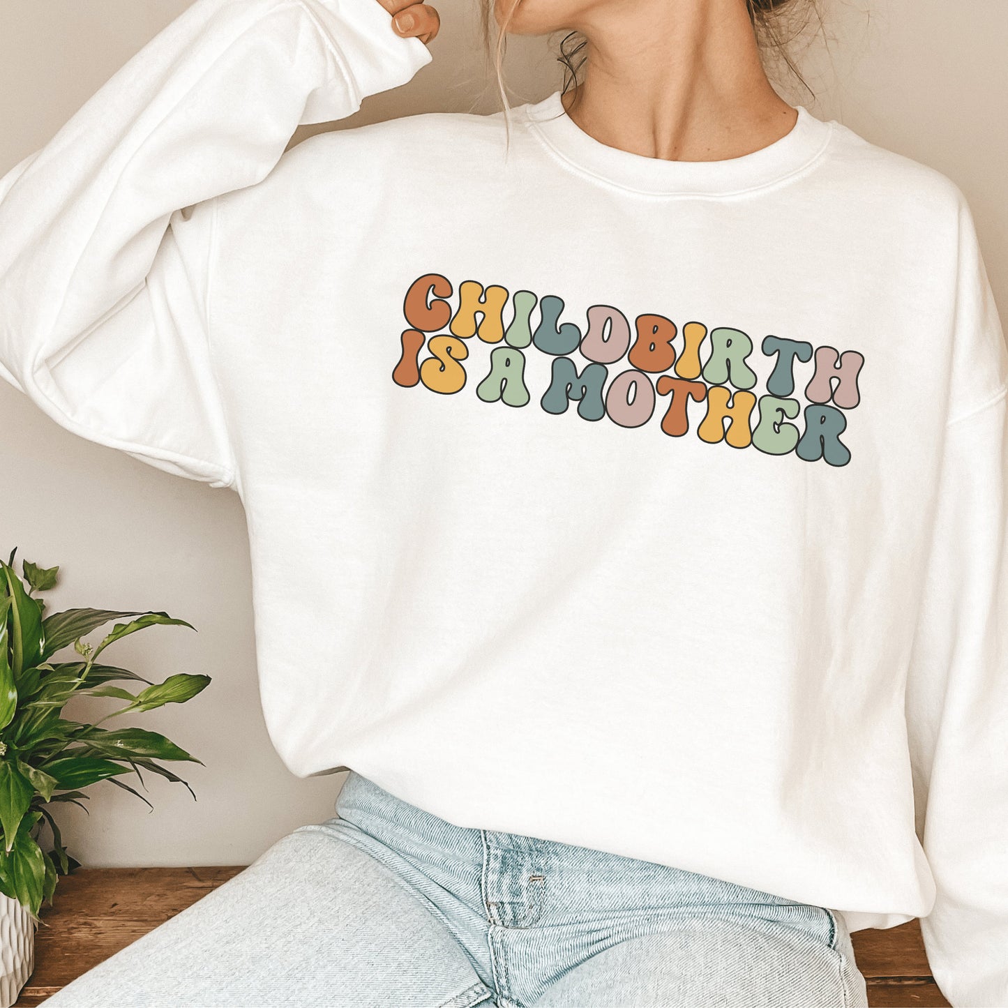 white unisex motherhood sweatshirt that says "childbirth is a mother" in retro styled multicolored all capital letters