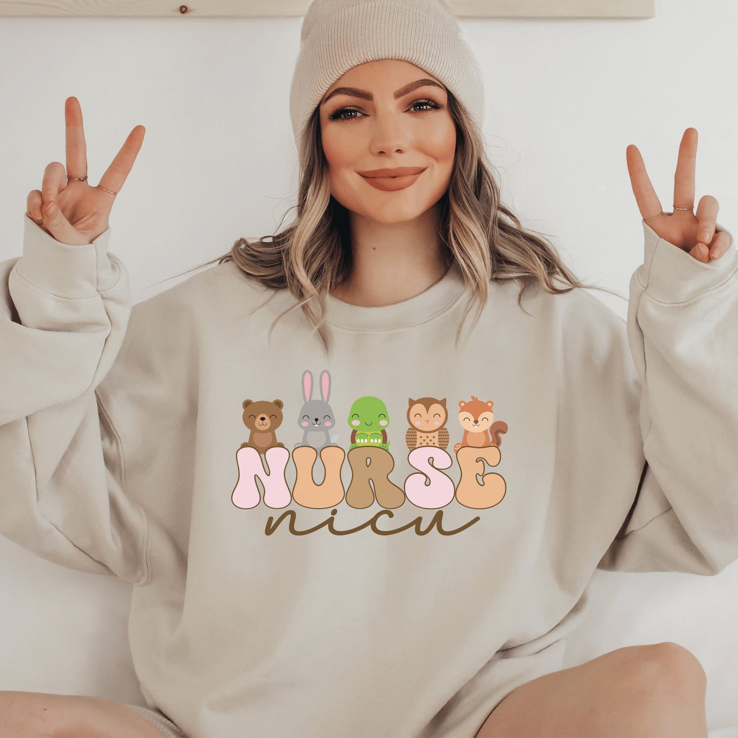 beige unisex nicu nurse sweatshirt with nurse in retro capital multicolored letters and the word nicu in brown script underneath. Baby animals are on top of the word nurse